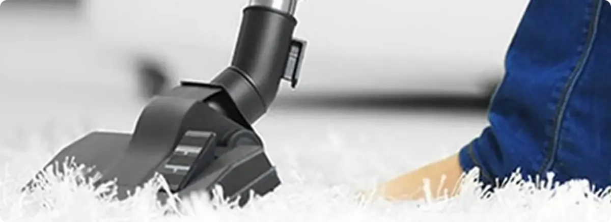 Close-up of a professional vacuuming a white carpet in North Little Rock.